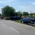 Ambulance and emergency responders on a sunny rural road at a two-car crash scene with one car off the road beside a fence.