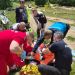 Emergency responders in red and dark uniforms attend to a person on the ground in a grassy off-road area, with dirt bikes nearby.