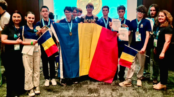 Group of young competitors holding Romanian and Ukrainian flags, wearing medals and certificates at an awards ceremony on stage.
