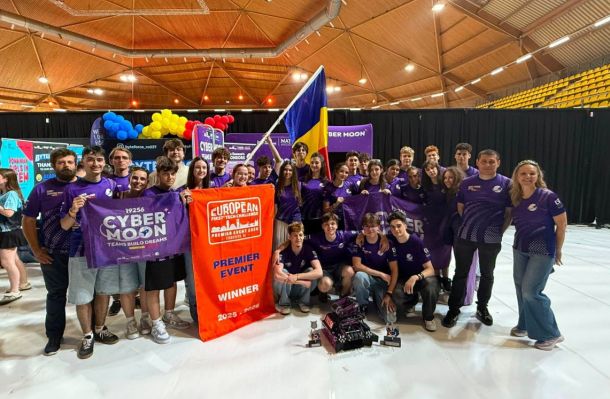 Group of students in purple team shirts posing with banners and a Ukrainian flag at a robotics competition, trophies on the floor, indoor arena backdrop