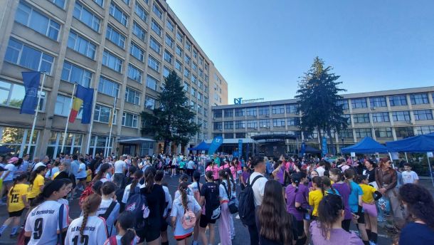 Crowd of students gathered in a university courtyard for a campus event, with blue tents and flags visible.