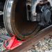 Close-up of a train wheel resting on the rail, with a red wedge wheel chock securing it